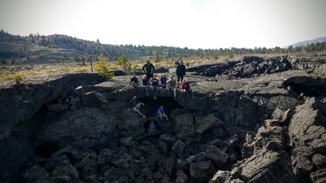 A group of students pose for a picture on top of a crumbled lava tube