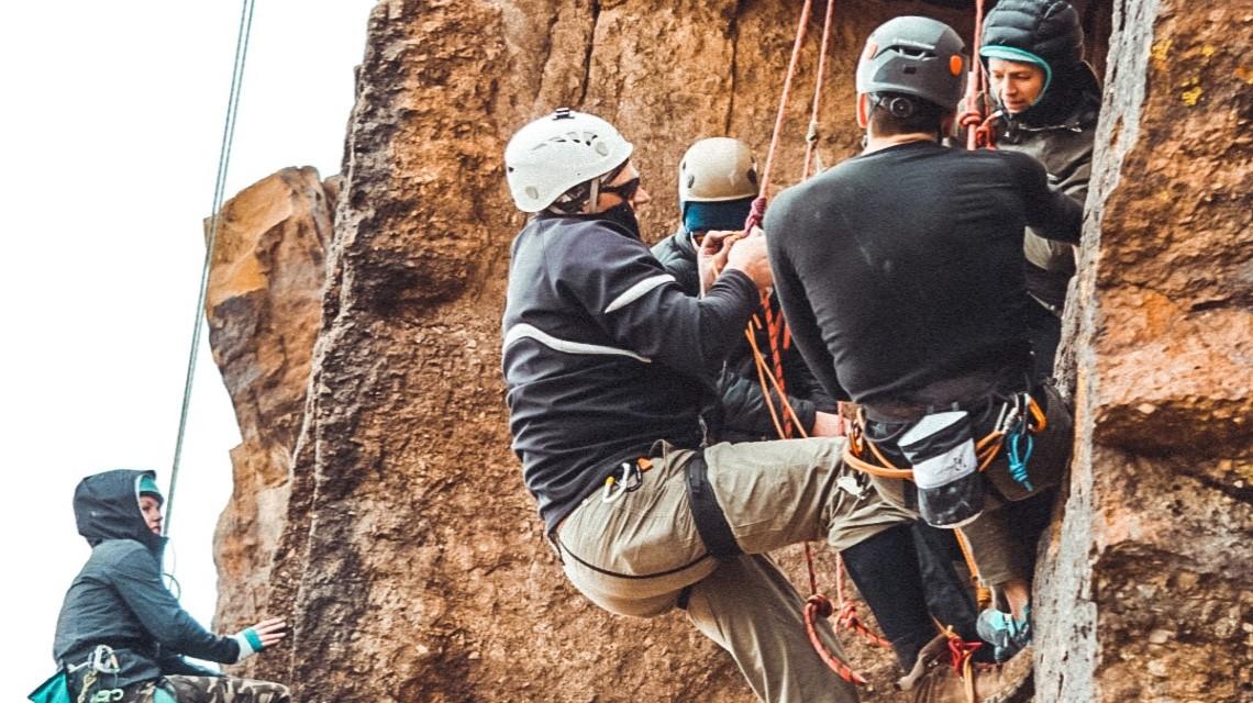 A group of students get ready to start scaling a cliff route