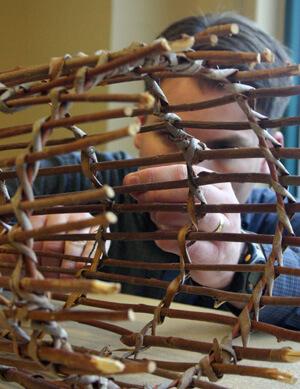 man weaving a fish trap from willow branches