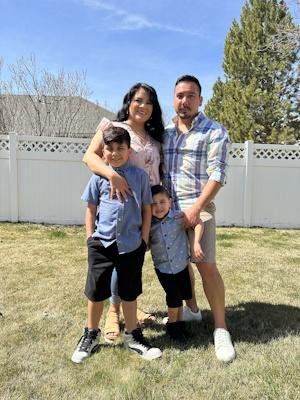 a young couple standing in a sunny backyard with their two young boys