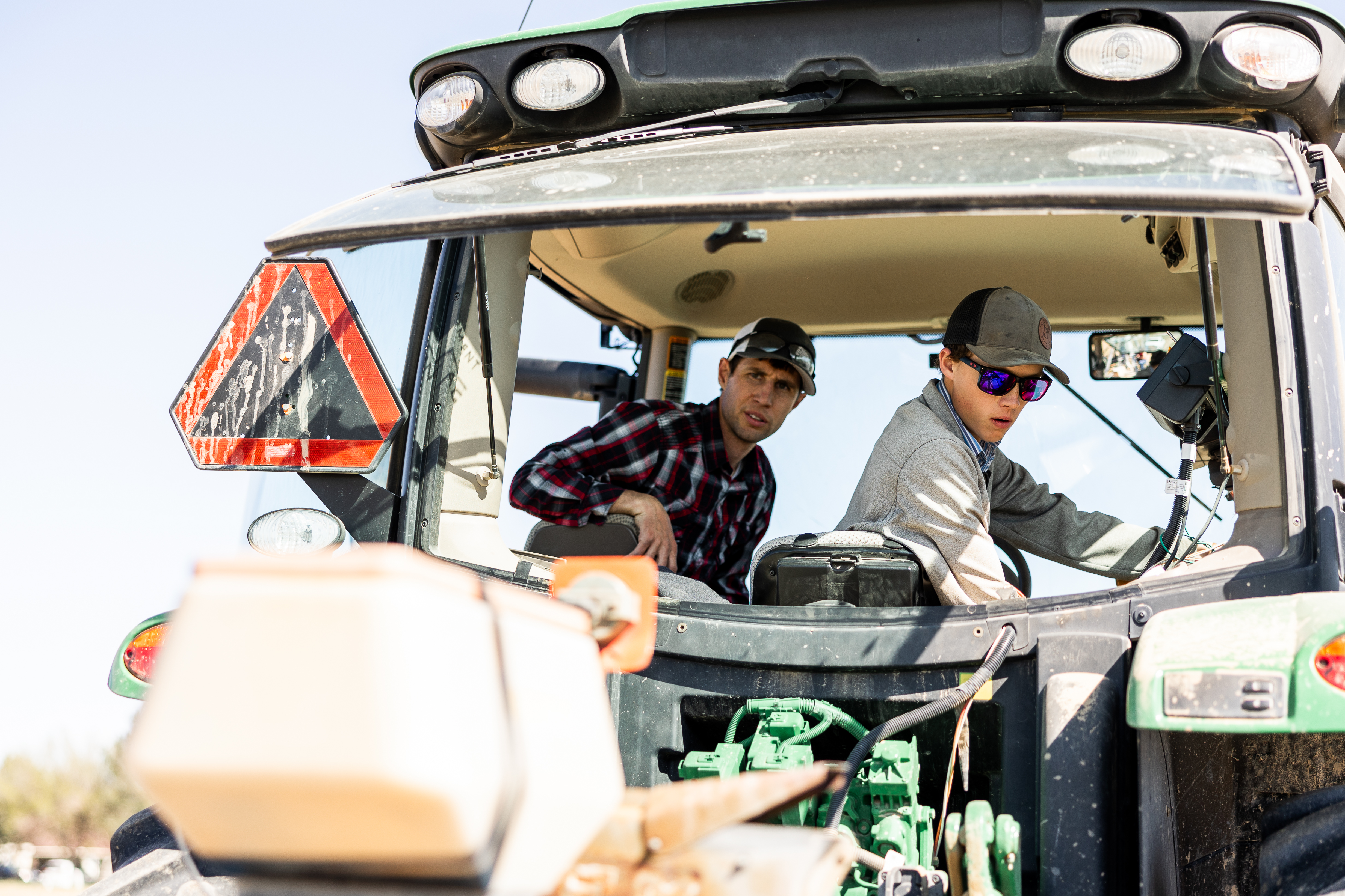 two people riding farm equipment