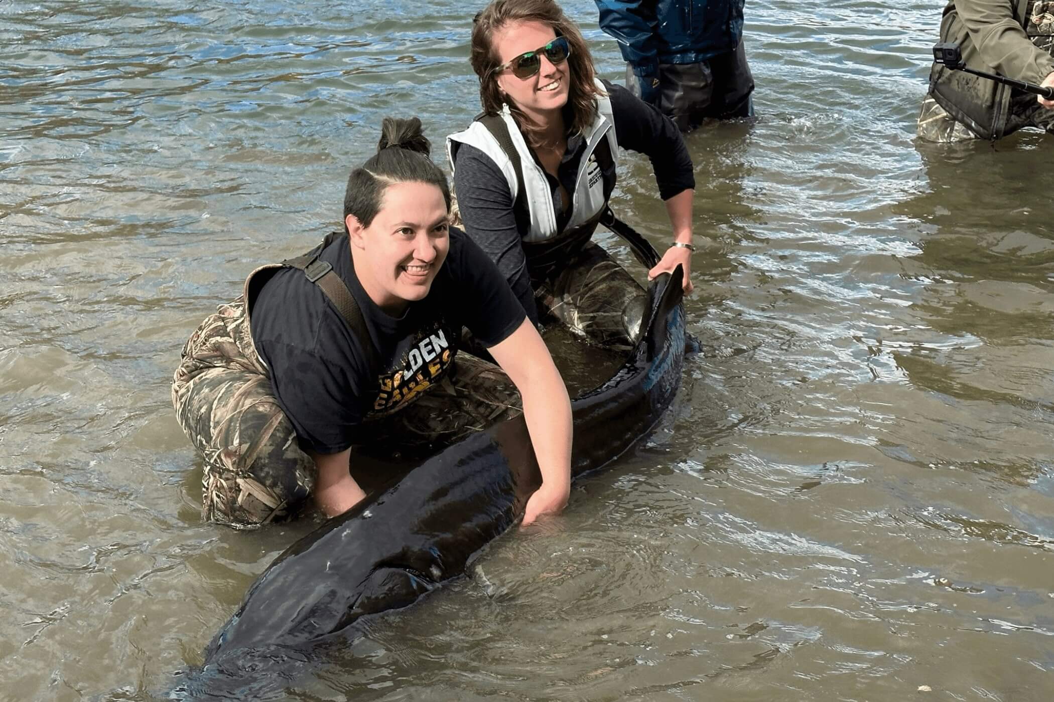aquaculture students holding a large sturgeon