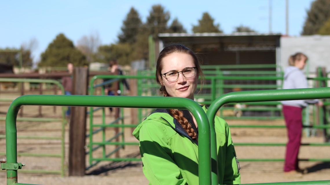 student standing behind gate outside