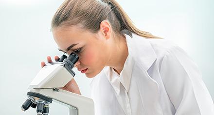 woman looking through microscope