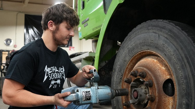 A ytoung man removing lug nuts with a large impact driver