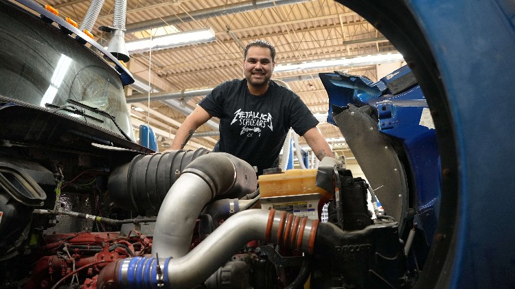 A man looking into the engine compartment of an 18 wheeler