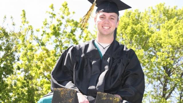 A young man in a graduation cap and gown