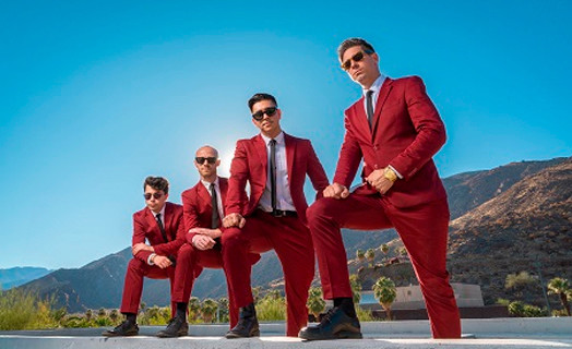 Picture of the 5 guys from the band wearing red suits