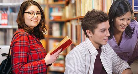 student holding a book in front of bookshelves