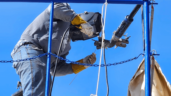 person welding something high up in the air