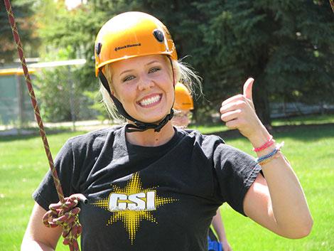 smiling woman in a rope harness about to climb