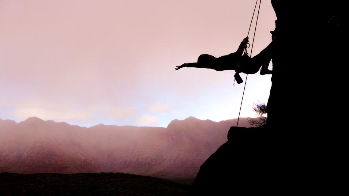 Student poses while hanging from their rock climbing gear