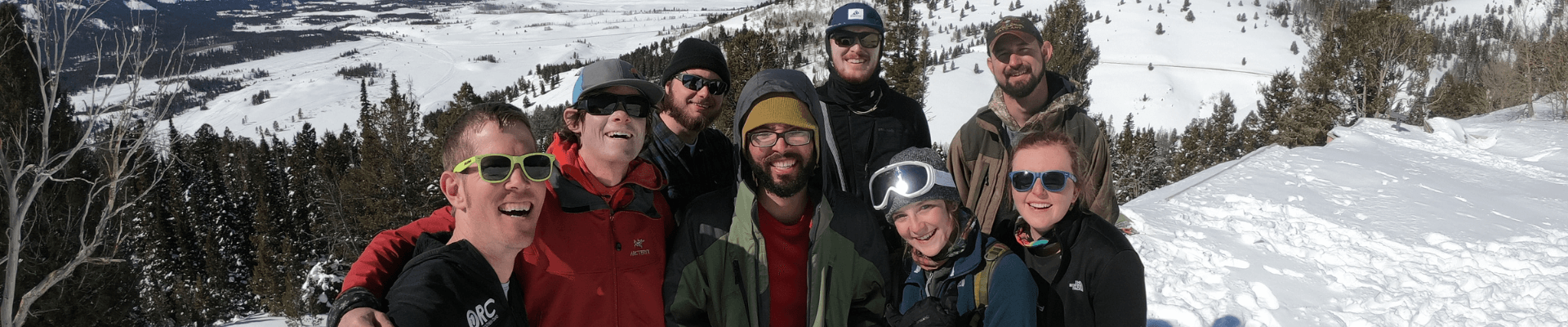 students in skiing clothes posing on a snowy mountainside