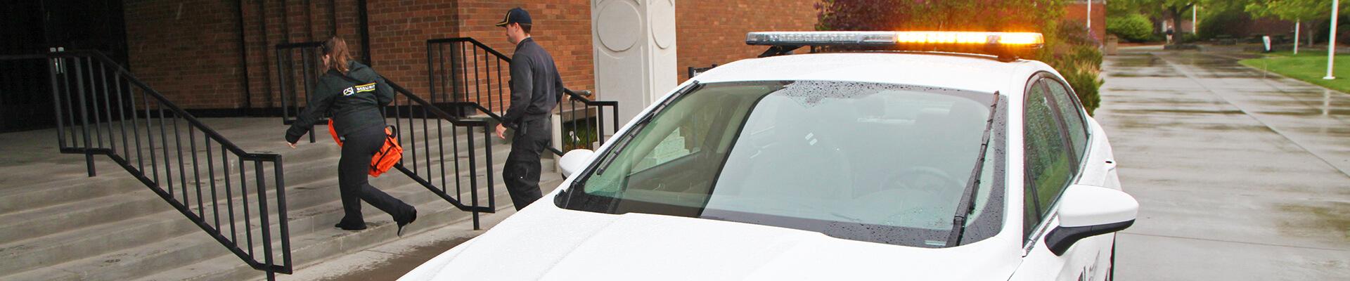 Security officers with first aid kits running into a building