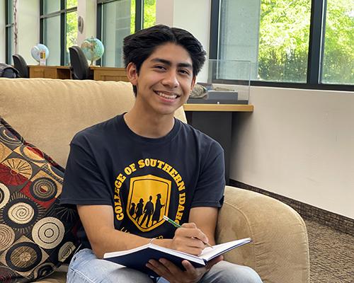 smiling student in CSI eagle shit, sitting in well lit dorm 