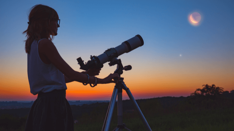 Girl looking at the moon with a telescope next to her